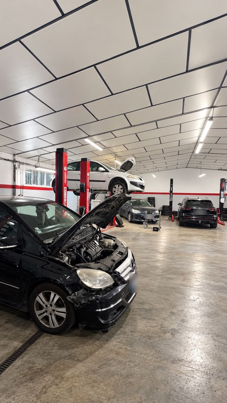 Voiture sur pont élévateur dans l’atelier, véhicules en cours d’intervention
